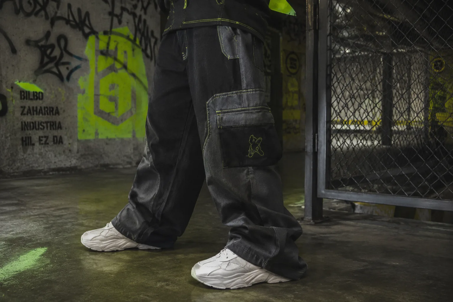 Cargo pants negros con costuras en amarillo electrico sobre suelo de hormigon